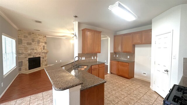 10208 Forest Spring Ln, Pearland, TX 77584 - kitchen featuring a sink, a peninsula, gas stove, dark stone counters, and ornamental molding