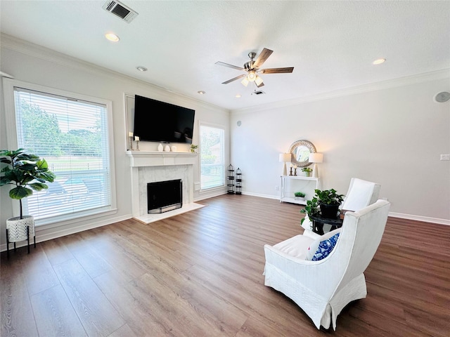 7210 Blenheim Palace Ln, Houston, TX 77095 - living room featuring a high end fireplace, a ceiling fan, baseboards, wood finished floors, and crown molding
