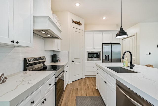 2515 103rd St, Galveston, TX 77554 - kitchen featuring appliances with stainless steel finishes, a sink, premium range hood, white cabinets, and recessed lighting