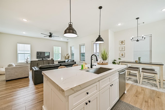 2515 103rd St, Galveston, TX 77554 - kitchen with a sink, stainless steel dishwasher, light wood finished floors, a chandelier, and white cabinets