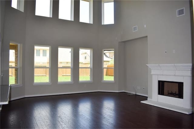 811 River Delta Ln, Rosenberg, TX 77469 - unfurnished living room with dark wood-style flooring, plenty of natural light, a towering ceiling, and a fireplace with raised hearth
