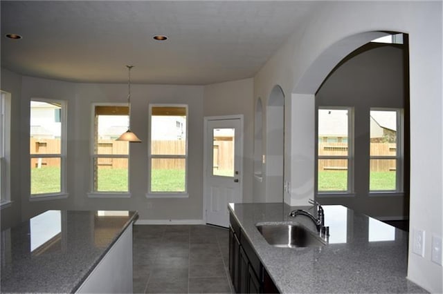 811 River Delta Ln, Rosenberg, TX 77469 - kitchen featuring dark stone counters, arched walkways, dark tile patterned flooring, hanging light fixtures, and recessed lighting