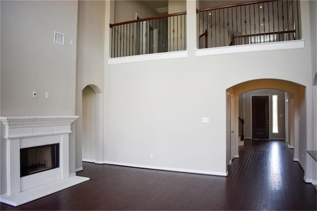 811 River Delta Ln, Rosenberg, TX 77469 - unfurnished living room with wood finished floors, a high ceiling, arched walkways, and a fireplace with raised hearth