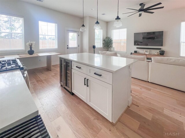 5402 Wheatley St Unit D, Houston, TX 77091 - kitchen featuring wine cooler, light wood finished floors, white cabinetry, a center island, and light countertops