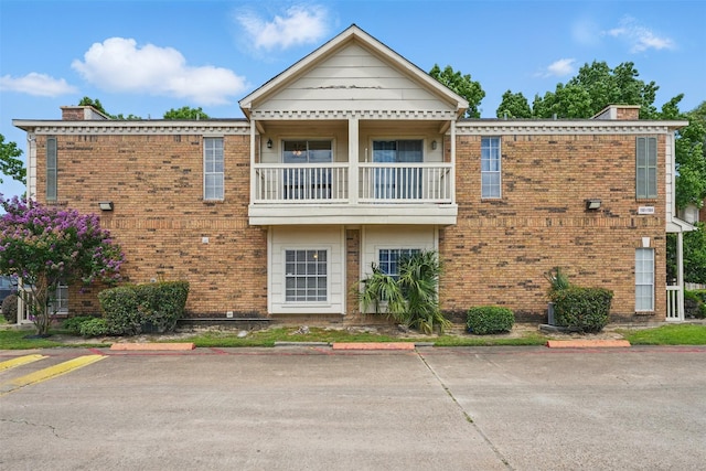 2626 Holly Hall St Unit 1102, Houston, TX 77054 - view of property featuring a balcony, a chimney, brick siding, and uncovered parking