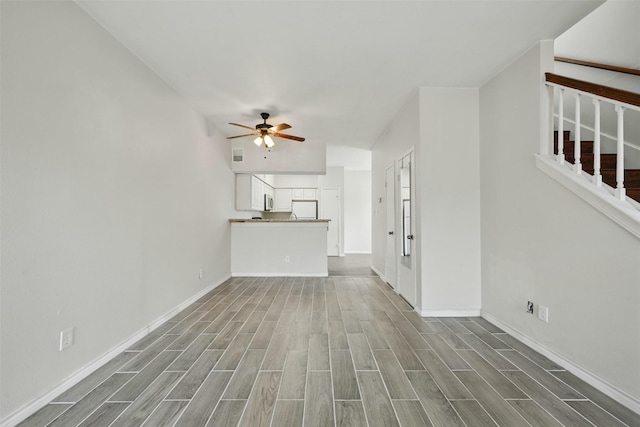 2626 Holly Hall St Unit 1102, Houston, TX 77054 - unfurnished living room featuring ceiling fan, wood finished floors, stairs, and baseboards