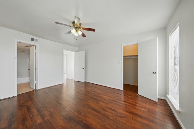 2626 Holly Hall St Unit 1102, Houston, TX 77054 - unfurnished bedroom featuring multiple windows, wood-type flooring, a walk in closet, and baseboards