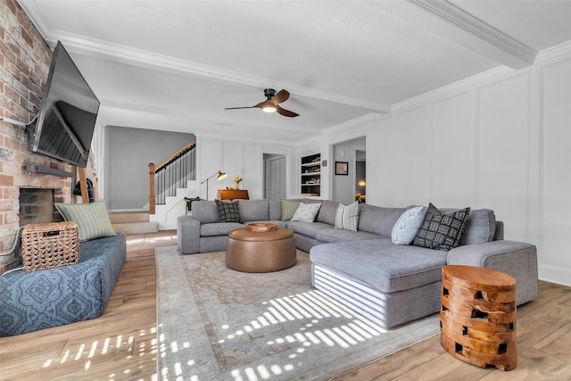 16310 Sir William Dr, Spring, TX 77379 - living room featuring wood finished floors, stairs, a brick fireplace, a decorative wall, and crown molding