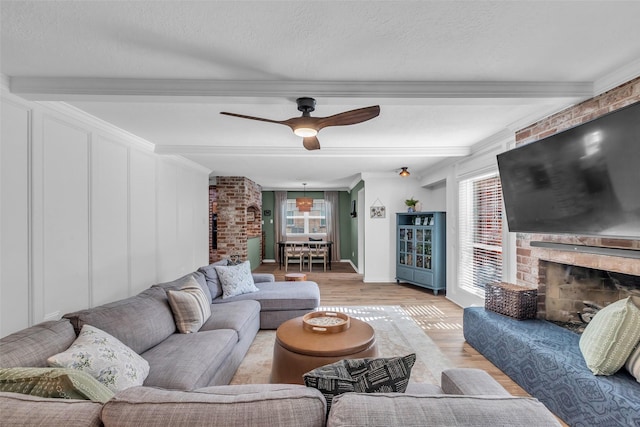 16310 Sir William Dr, Spring, TX 77379 - living room with beamed ceiling, light wood-style floors, a fireplace, ceiling fan, and crown molding