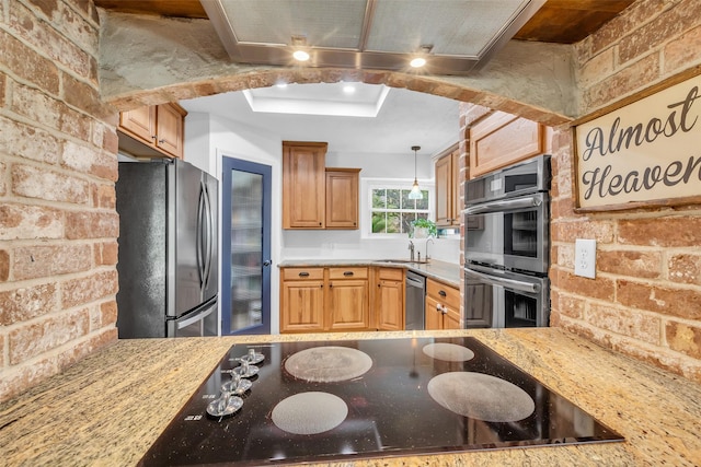 16310 Sir William Dr, Spring, TX 77379 - kitchen featuring stainless steel appliances, brick wall, a sink, pendant lighting, and light stone countertops