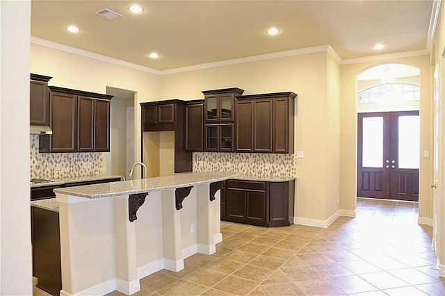 4914 Ava Meadows Ln, Sugar Land, TX 77479 - kitchen featuring a kitchen island with sink, french doors, tasteful backsplash, a breakfast bar area, and recessed lighting