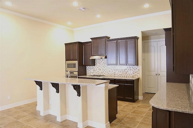 4914 Ava Meadows Ln, Sugar Land, TX 77479 - kitchen featuring appliances with stainless steel finishes, an island with sink, backsplash, a breakfast bar area, and recessed lighting