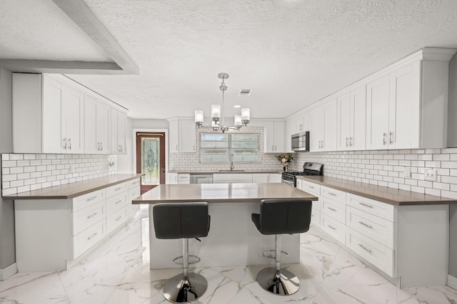 2701 Oaks Dr, Pasadena, TX 77502 - kitchen with stainless steel appliances, a sink, a textured ceiling, light marble finish floors, and backsplash