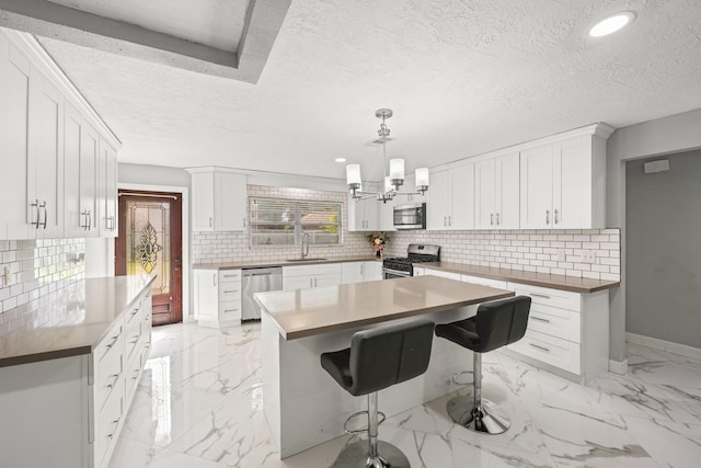 2701 Oaks Dr, Pasadena, TX 77502 - kitchen with stainless steel appliances, light marble finish flooring, a textured ceiling, decorative backsplash, and baseboards