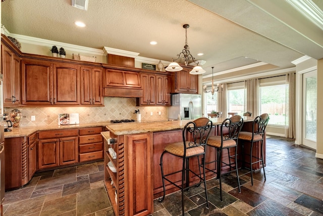 51 Northwood Ct, Lake Jackson, TX 77566 - kitchen featuring stainless steel appliances, ornamental molding, brown cabinets, stone tile flooring, and a kitchen island