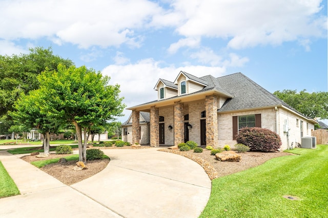 51 Northwood Ct, Lake Jackson, TX 77566 - view of front of home with central AC, stone siding, a front yard, curved driveway, and roof with shingles