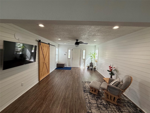 2044 Des Jardines St, Houston, TX 77023 - living area with wood walls, a barn door, dark wood-style floors, a textured ceiling, and recessed lighting