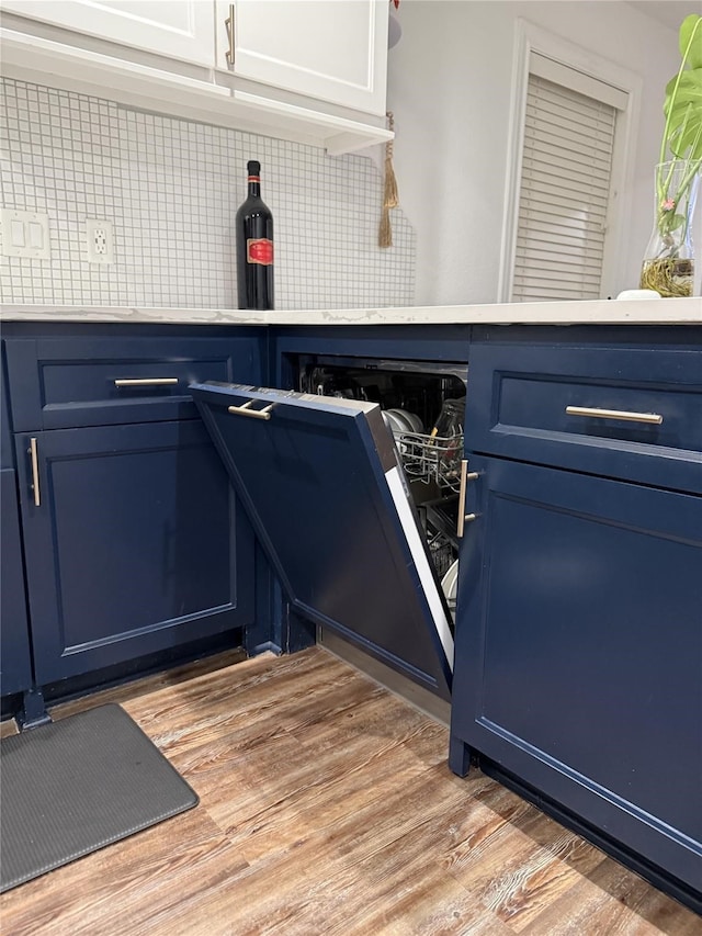 2044 Des Jardines St, Houston, TX 77023 - kitchen view of blue cabinetry, light wood finished floors, tasteful backsplash, and light countertops