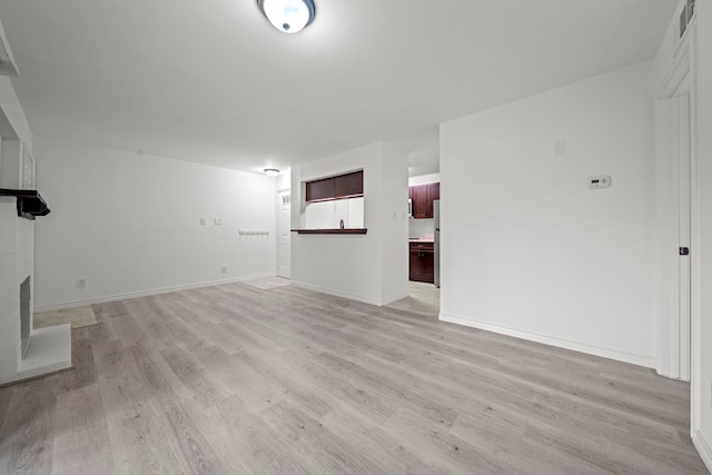 3500 Tangle Brush Dr Unit 48, The Woodlands, TX 77381 - unfurnished living room featuring light wood-style floors, a brick fireplace, and baseboards