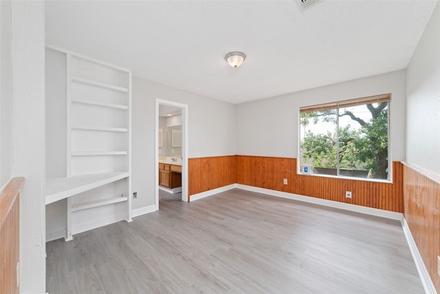 14651 Via Del Norte Dr, Houston, TX 77083 - empty room featuring wainscoting, wooden walls, light wood-style floors, and built in features