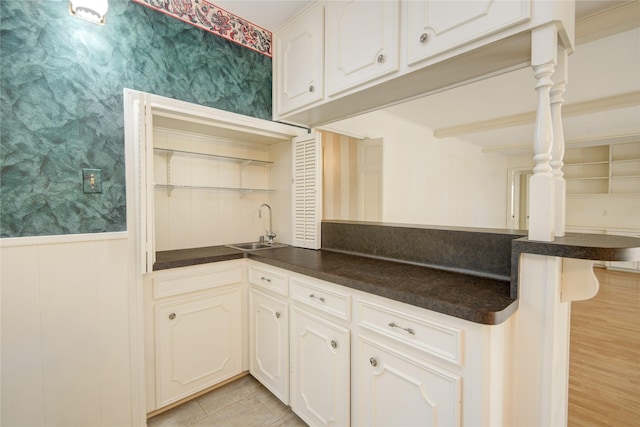 10902 Brentway Dr, Houston, TX 77070 - kitchen with wallpapered walls, dark countertops, a peninsula, a wainscoted wall, and white cabinetry