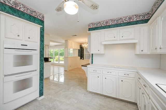 10902 Brentway Dr, Houston, TX 77070 - kitchen with white double oven, white cabinetry, cooktop, a chandelier, and ceiling fan