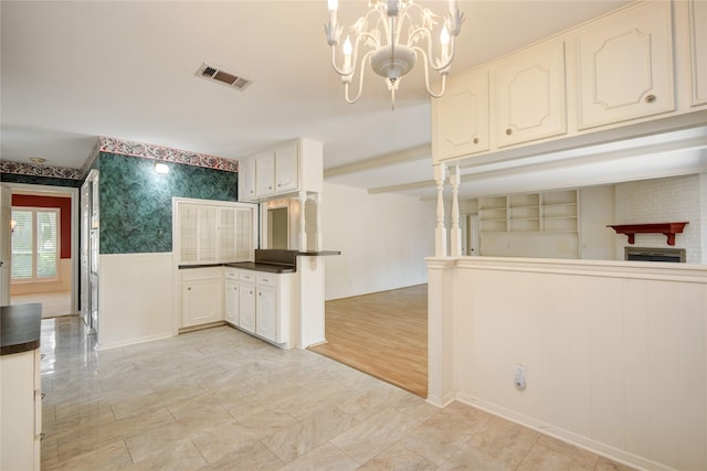 10902 Brentway Dr, Houston, TX 77070 - kitchen featuring dark countertops, wallpapered walls, a chandelier, wainscoting, and white cabinets