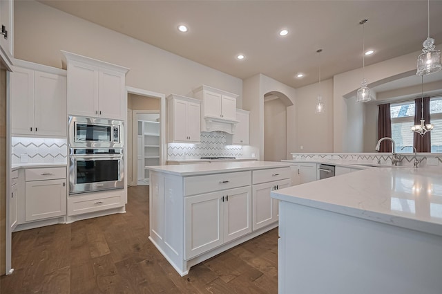 17414 Orchid Falls Ln, Conroe, TX 77302 - kitchen featuring appliances with stainless steel finishes, a sink, backsplash, white cabinets, and a center island