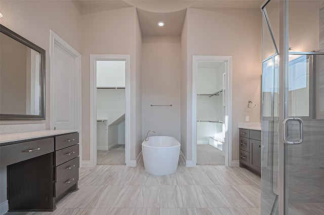 17414 Orchid Falls Ln, Conroe, TX 77302 - bathroom featuring vanity, a spacious closet, a shower stall, a soaking tub, and baseboards