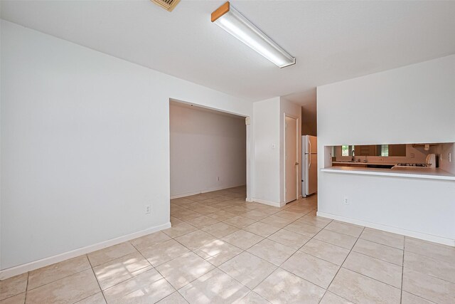 10111 Woodico Ct, Houston, TX 77038 - empty room featuring light tile patterned floors, a sink, and baseboards