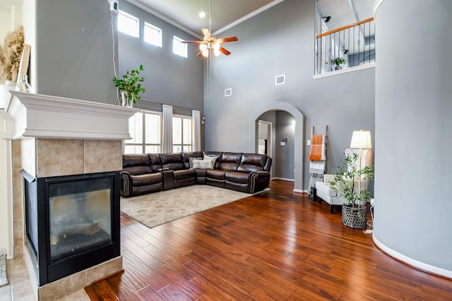 8423 Glenn Leigh Dr NE, Spring, TX 77379 - living room featuring arched walkways, ceiling fan, wood-type flooring, a tiled fireplace, and baseboards