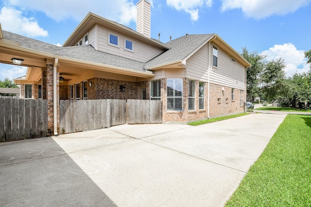 8423 Glenn Leigh Dr NE, Spring, TX 77379 - back of house featuring ceiling fan, brick siding, driveway, a chimney, and a shingled roof
