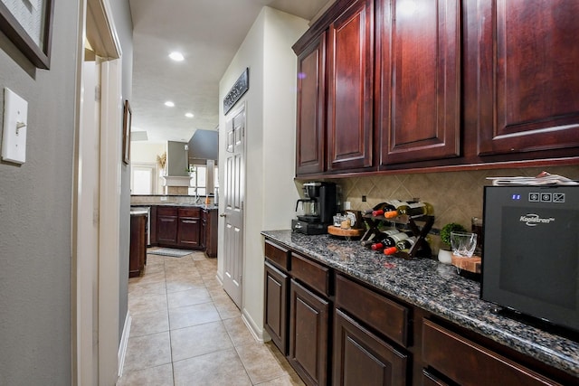 8423 Glenn Leigh Dr NE, Spring, TX 77379 - kitchen with backsplash, light tile patterned flooring, dark brown cabinets, dark stone counters, and a sink