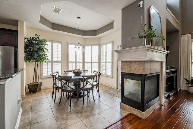 8423 Glenn Leigh Dr NE, Spring, TX 77379 - dining area featuring baseboards, a raised ceiling, a tiled fireplace, and a chandelier