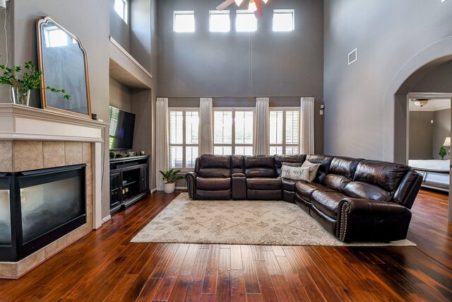8423 Glenn Leigh Dr NE, Spring, TX 77379 - living area with a towering ceiling, ceiling fan, arched walkways, a tiled fireplace, and dark wood-type flooring