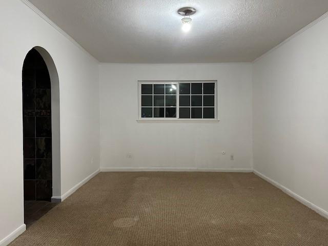 9719 Lawngate Dr, Houston, TX 77080 - unfurnished room featuring carpet, arched walkways, and a textured ceiling