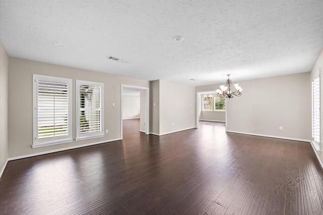 15414 Ashburton Dr, Jersey Village, TX 77040 - unfurnished living room featuring a chandelier, a textured ceiling, and dark wood finished floors
