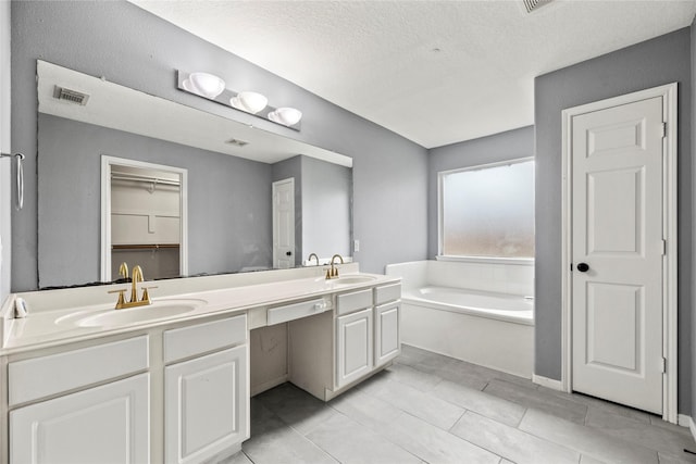 4130 Tree Moss Pl, Humble, TX 77346 - full bath featuring a bath, double vanity, tile patterned flooring, a textured ceiling, and a spacious closet