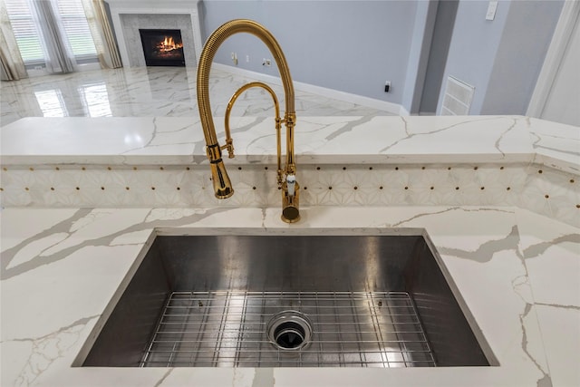 4130 Tree Moss Pl, Humble, TX 77346 - kitchen view of a sink, light stone countertops, and a glass covered fireplace