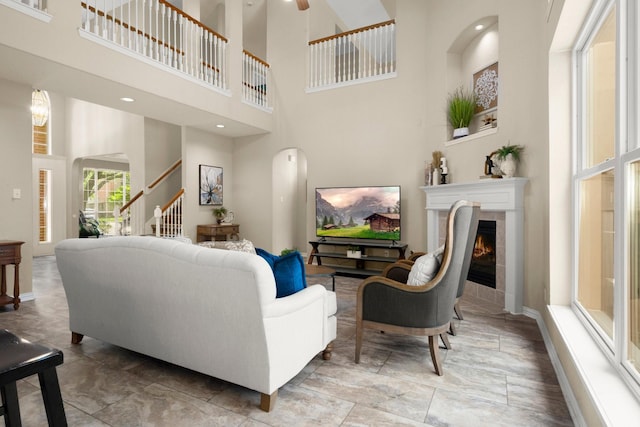 9607 Woodcliff Lake Dr, Spring, TX 77379 - living room featuring a towering ceiling, a fireplace, stairway, ceiling fan, and baseboards