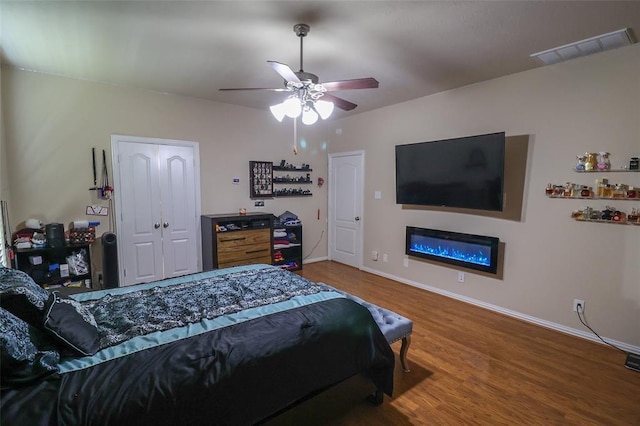 9911 Clear Diamond Dr, Rosharon, TX 77583 - bedroom featuring wood finished floors, baseboards, a glass covered fireplace, and ceiling fan