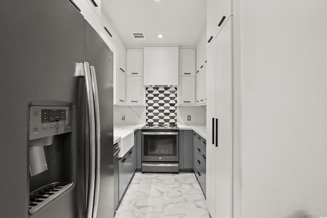 3414 Cline St, Houston, TX 77020 - kitchen with stainless steel appliances, light marble finish flooring, white cabinets, light countertops, and custom range hood