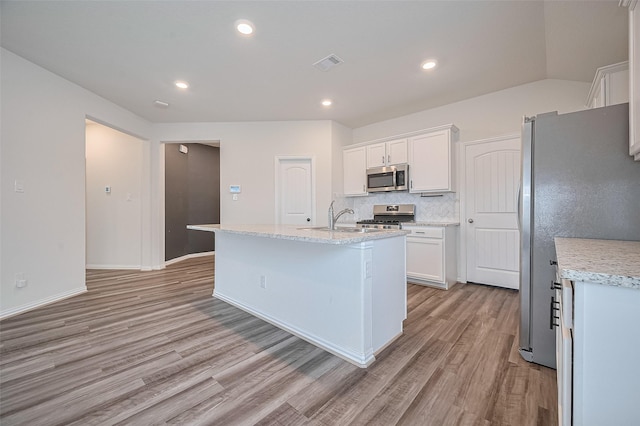 20231 Creekdale Bend Dr, Cypress, TX 77433 - kitchen featuring stainless steel appliances, light wood-style flooring, white cabinets, a center island with sink, and tasteful backsplash