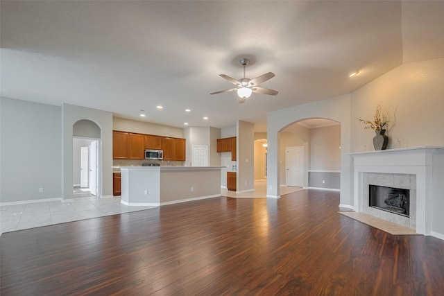 13409 Timberoak Ct, Rosharon, TX 77583 - unfurnished living room with ceiling fan, arched walkways, a fireplace, light wood finished floors, and recessed lighting