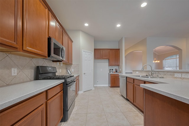 13409 Timberoak Ct, Rosharon, TX 77583 - kitchen with stainless steel appliances, a sink, brown cabinetry, arched walkways, and backsplash