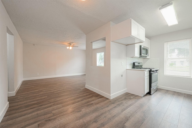 12111 Jutland Rd, Houston, TX 77048 - kitchen featuring appliances with stainless steel finishes, wood finished floors, ceiling fan, a textured ceiling, and white cabinetry
