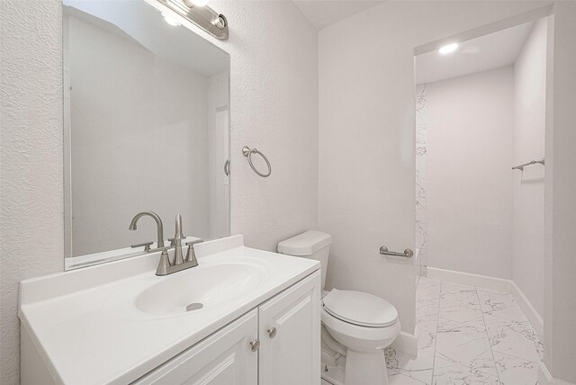 12111 Jutland Rd, Houston, TX 77048 - bathroom with marble finish floors, toilet, vanity, a textured wall, and baseboards