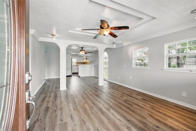 1118 Hammock St, Houston, TX 77009 - unfurnished living room with arched walkways, a ceiling fan, a textured ceiling, a tray ceiling, and wood finished floors