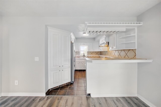 1118 Hammock St, Houston, TX 77009 - kitchen with under cabinet range hood, white cabinetry, backsplash, and a peninsula