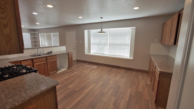 1203 Brook Grove Dr, Katy, TX 77450 - kitchen featuring tasteful backsplash, a sink, light wood finished floors, brown cabinets, and baseboards